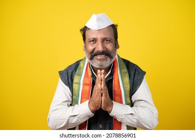 Indian Politician greeting by doing namaste - Concept of welcome gesture showing on yellow background.