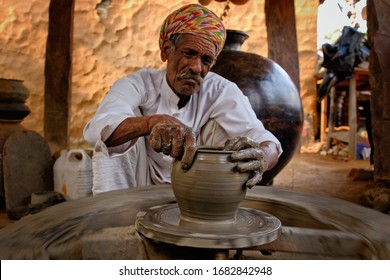 Indian Potter At Work: Throwing The Potter's Wheel And Shaping Ceramic Vessel And Clay Ware: Pot, Jar In Pottery Workshop. Experienced Master. Handwork Craft From Shilpgram, Udaipur, Rajasthan, India