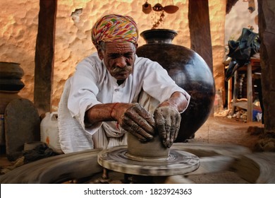 Indian Potter At Work: Throwing The Potter's Wheel And Shaping Ceramic Vessel And Clay Ware: Pot, Jar In Pottery Workshop. Experienced Master. Handwork Craft From Shilpagram, Udaipur, Rajasthan, India