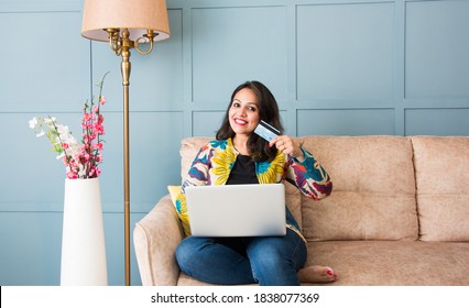 Indian pretty woman or girl using debit or credit card for online shopping on laptop computer