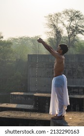 Indian priest praying to Sun, indian priest praying to surya while dropping water in showing respect to god.