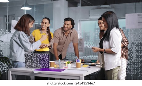 Indian professional business people standing at indoor office use laptop listening project meeting discussion. Confident teenager female teach interns staff group having communication multiple team - Powered by Shutterstock