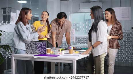 Indian professional business people standing at indoor office use laptop listening project meeting discussion. Confident teenager female teach interns staff group team enjoy work together at workplace
