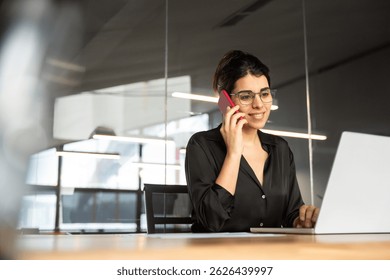 Empresaria profesional india que habla con el cliente del negocio, usando el teléfono y la computadora de la PC para el trabajo Mujer ejecutiva joven del gerente que trabaja en la computadora portátil, teniendo llamada telefónica en la oficina corporativa