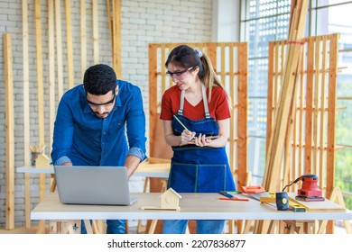 Indian Professional Male Engineer Foreman Labor Worker Using Laptop Computer Meeting Discussing With Cheerful Female Colleague Wear Safety Goggles Writing Note On Paper Clipboard In Construction Site.