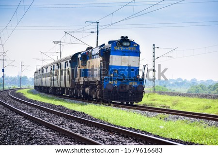 An Indian Railways Diesel Locomotive of type WDM3A accelerating hard and passes through a curved track after a scheduled halt at a suburb station.