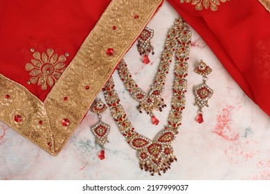 Indian Red Cloth With Gold Border Sari And Jewelry On A Light Background. Wedding Dress