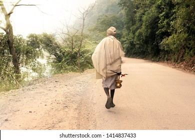 Indian renounced sadhu leaves on the way to the forest. A wandering wanderer with a trident and a kamandala. Photo from the back.