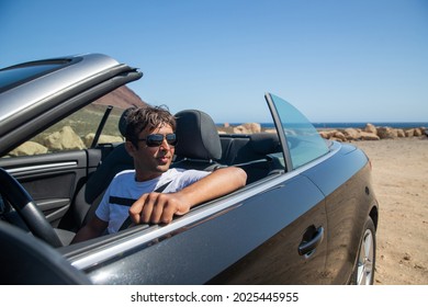 Indian Rich Man Sitting In His Convertible Car Wears Sunglasses And Looks To The Side. Realized Man Sitting In An Expensive Car. Forty Year Old Person Of Indian Ethnicity