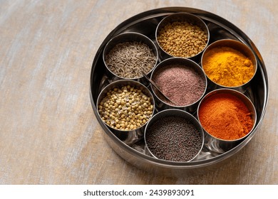 Indian round spices box or Indian masala dabba with seven containers on a wooden table. - Powered by Shutterstock