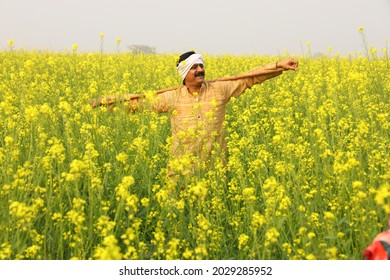 Indian rural happy farmer in village in a mustard field in a green farm yellow flowers. - Powered by Shutterstock