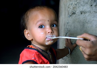 Indian Rural Mother Feeding Her 10 Months Baby Girl With Spoon, First Solid Food For Kid, Selective Focus