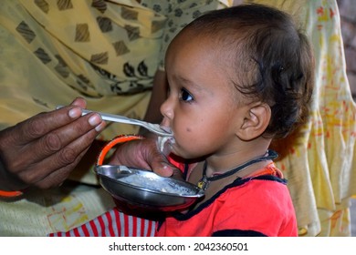 Indian Rural Mother Feeding Her 10 Months Baby Girl With Spoon, First Solid Food For Kid, Selective Focus