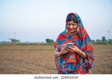 Indian rural woman in traditional saree and using smartphone at agriculture field. - Shutterstock ID 2244516319