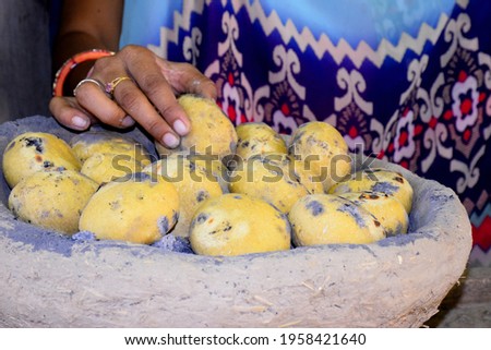 Indian rural woman's hands baking bread in earthen pot.