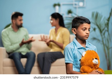 Indian sad kid with doll in front shouting and arguing couple at home - concept of family conflict, childhood trauma and emotional distress. - Powered by Shutterstock