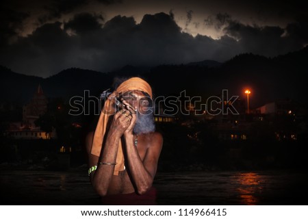Indian sadhu smoking hashish on Ganges riverbank