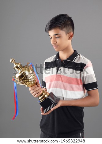 Indian school boy holding a golden trophy cup