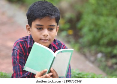 Indian Schoolboy Reading A Book In The Garden	
