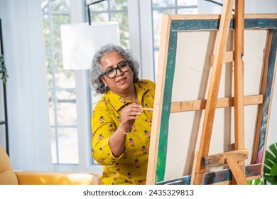 Indian Senior Female Artist Working On Painting In Studio on easel - Powered by Shutterstock