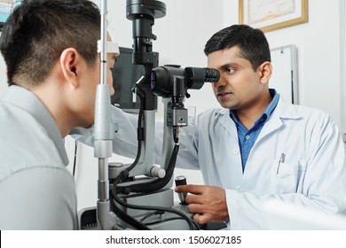 Indian serious optometrist working with his patient he using special medical equipment and examining the eyesight at hospital