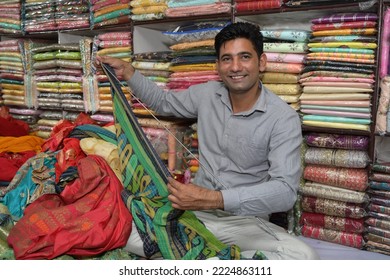 An Indian shopkeeper showing clothes from his store - Shutterstock ID 2224863111