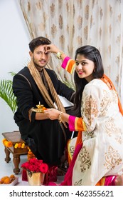 indian sister applying tika on brother's forehead, enjoying and Indian good looking young brother and sister celebrating Raksha Bandhan / Rakhi  festival or on Bhai dooj/Bhau-Beej with Poja Thali, swe