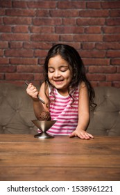 Indian Small Girl Eating Ice Cream In A Bowl