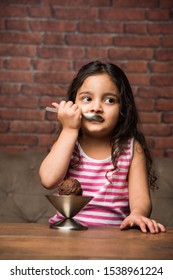 Indian Small Girl Eating Ice Cream In A Bowl