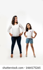 Indian Small Girl And Mother Standing Over White Background Measuring Height Difference