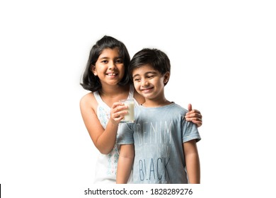 Indian small siblings or friends holding or having a glass full of milk against white background