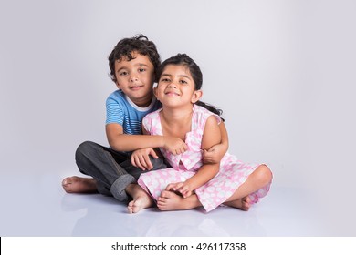 Indian Small Siblings Hugging / Cuddling, Sitting Over White Background