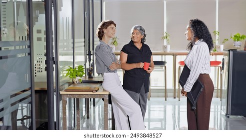 Indian smiling old business women standing hold cup drink coffee talk gossip indoor work place. Beautiful young adult corporate girls make funny blab share ideas during tea break spend time job office - Powered by Shutterstock