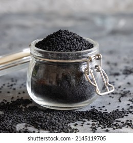 Indian Spice Black Cumin (nigella Sativa Or Kalonji) Seeds Glass Jar On Grey Table Close Up. Traditional Asian Medicine, Healthy And Vegetarian Food Concept