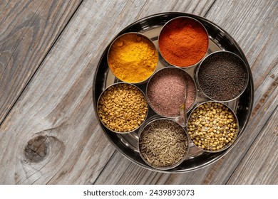 Indian spices box or Indian masala dabba with seven containers on rustic wooden table. Top view. - Powered by Shutterstock