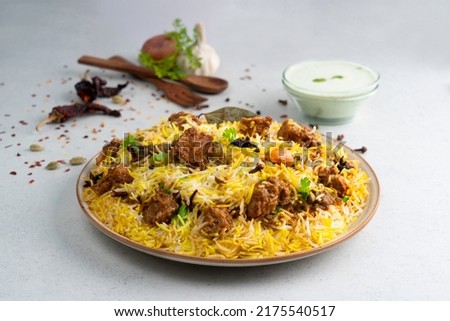 Indian spicy mutton Biryani with raita and gulab jamun Served in a dish side view on grey background