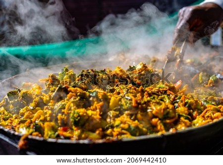 indian street cooking in London.Steam and heat rising from the delicious pan of curry.Mouth watering food created by market stall chef.The trend continues for exciting recipes from all over the World