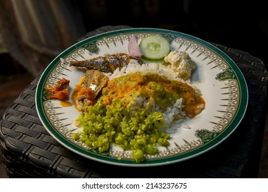 indian Style Food Rice and Fish on white color plate. pickle, cucumber,curry. 
