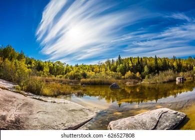Indian summer in Manitoba, Canada. Incredible cirrus clouds over the Winnipeg River. Old Pinawa Dam Park. The concept of ecological and recreational tourism