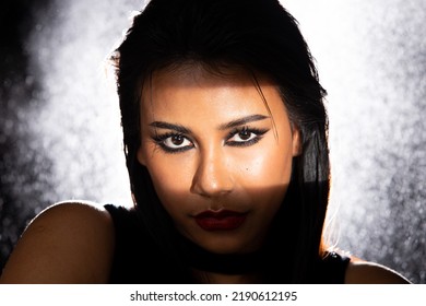 Indian Tanned Skin Asian Woman Show Face Make Up With Backlit Light And Water Splash Spray. Shadow Silhouette Female Head Express Feeling Dramatic Over Beautiful Elegance Black Background Copy Space