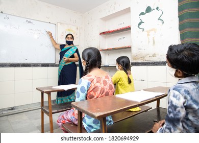 Indian Teacher And Students Wearing Face Masks  Study In Classroom Back At School During Covid19 Pandemic. Government School Of India.