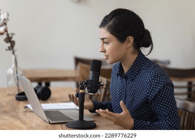Indian teacher woman use laptop, professional microphone, give webinar, make speech, lead on-line lecture, record podcast, share skills, hold online class for subscribers, teach audience. Livestream