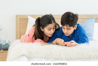 Indian Teenage Adorable Boy, Girl Sibling Laying Down On Bed, Playing, Reading Book And Doing Homework Together With Fun And Happiness At Cozy Home In A Day. Lifestyle, Family, Education Concept