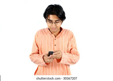 An Indian teenage boy wearing a traditional kurta sending a sms on his cellphone.