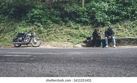 Indian tourists taking a break from riding their bike by a highway in Kodai, Tamil Nadu, India shot on January 2020....