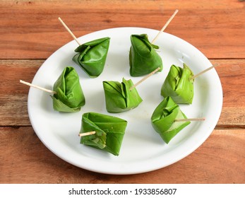 Indian Traditional Mouth Freshener Sweet Paan wrapped in betel leaf, often used as an after dinner digestive. served over a white plate on a rustic wooden background, selective focus