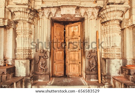 Indian traditional style design at entrance of historical Hindu temple with collumns, wooden door and sculptures, India