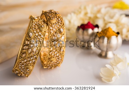 Indian traditional wedding jewellery, bangles with huldi kumkum and white flowers. selective focus