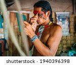 Indian from the Pataxó tribe, using a mirror and doing face painting.