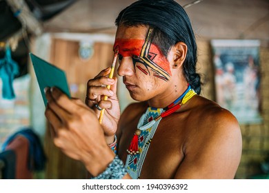 Indian from the Pataxó tribe, using a mirror and doing face painting.